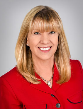Headshot of Dr. Dianna Milewicz, a blonde doctor wearing a red blazer